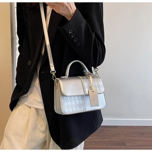 Close-up of a silver quilted leather handbag featuring a sleek handle and metal buckle