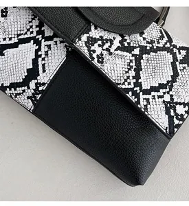 Detail of snakeskin and lychee grain faux leather stitching on women crossbody bag