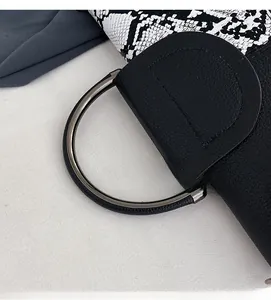 Detail of black lychee grain leather handbag with snake pattern flap and round metal handle