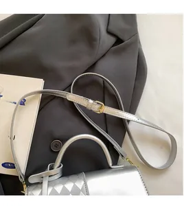 Detail of silver quilted crossbody bag with adjustable strap on a grey blazer