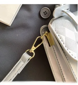 Detail of light gray quilted leather handbag with glossy gold metal hook hardware