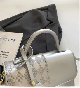 Close-up of silver quilted crossbody bag with circular metal handle and geometric texture