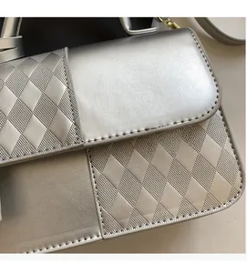 Detailed macro of silver quilted texture fabric and gold hardware on a designer handbag