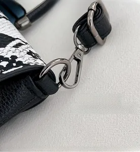 Detailed close-up of dark grey metal lobster clasp and snakeskin pattern on handbag