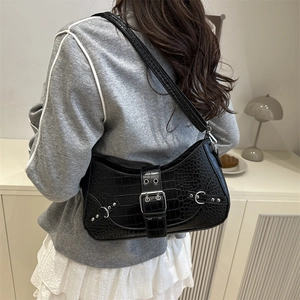 Stylish black crocodile pattern underarm bag with silver buckles in a chic lifestyle setting