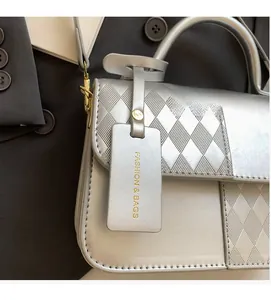 Detail of silver quilted handbag featuring a round handle and fashion brand tag