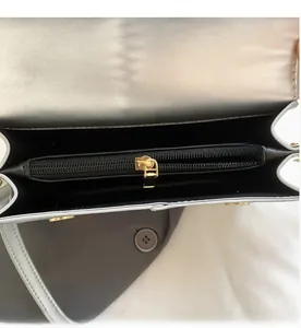 Detail view of the smooth golden metal zipper and black inner compartment of the handbag
