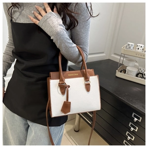Détail d'un sac à main blanc contrasté avec poignées marron et bandoulière amovible