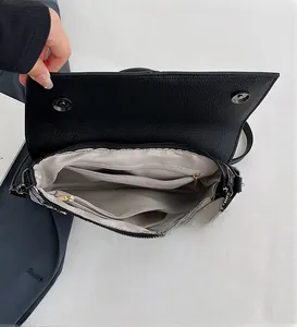 Detail view showing multi-compartment interior and grey lining of black leather handbag