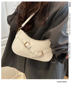 Detail of white crocodile pattern underarm bag with gold buckles and chic strap