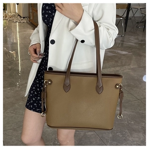 Detail of a khaki and dark brown contrast tote bag featuring pebble grain texture and metal ring