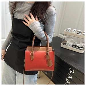 Détail du sac à main rouge et marron avec texte doré Fashion and Bags élégant