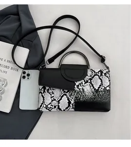 Detail of snake skin pattern and black pebbled leather texture on a crossbody bag