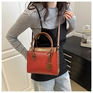 Vue portée d'un sac bandoulière rectangulaire rouge brique avec poignées marron foncé