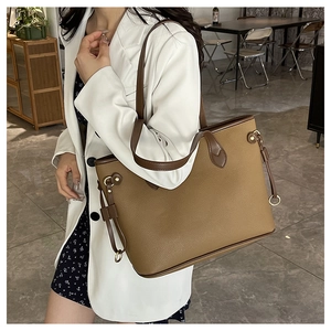 Brown leather tote bag with pebble texture and metal ring detail worn for work