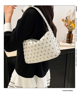 Vue détaillée d'un sac hobo blanc en forme de lune avec des rivets métalliques
