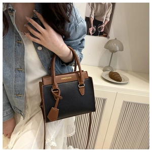 Sac bandoulière chic bicolore noir et marron présenté dans un décor d'intérieur moderne