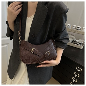 Detail of dark brown crocodile pattern bag with gold buckles and detachable strap