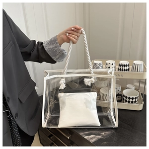 Close-up of a transparent PVC tote bag with thick white rope handles and inner pouch