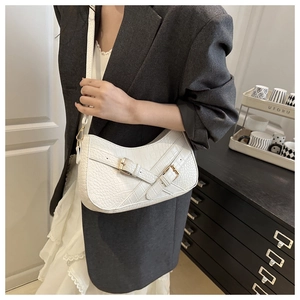 Detail of white crocodile texture underarm bag with gold buckles and crescent shape