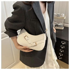 Detail of white crocodile pattern half-moon shoulder bag with golden buckles on model
