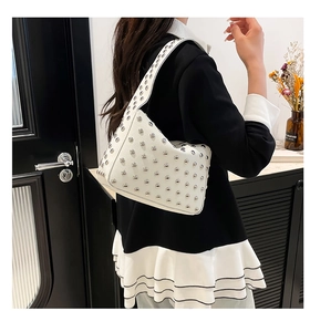 Dettaglio della borsa a spalla bianca in pelle con fitte borchie metalliche argento