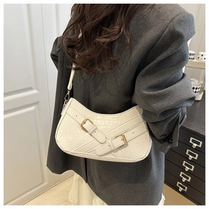 Detail view of white crocodile pattern shoulder bag with golden buckles on model