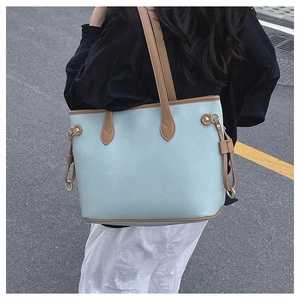 Detail of light blue lychee pattern leather tote bag with brown trim and gold hardware