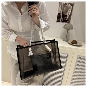 Lifestyle shot of transparent black PVC tote bag with white rope handles in a minimalist room