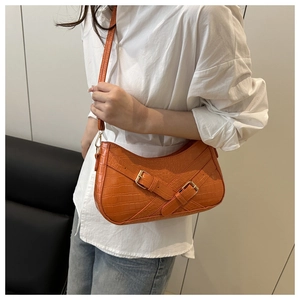 Detail of vibrant orange crocodile pattern underarm bag with decorative metal buckles