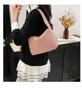 Détail du sac à main croissant rose avec rivets argentés et texture cuir grainé