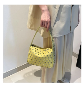 Détail d'un sac à main punk jaune avec clous argentés ronds et finition en cuir mat