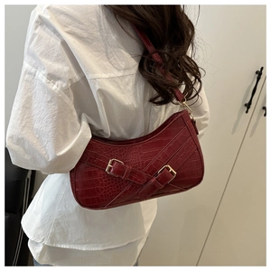 Close-up of wine red faux leather baguette bag with crocodile texture and gold buckle