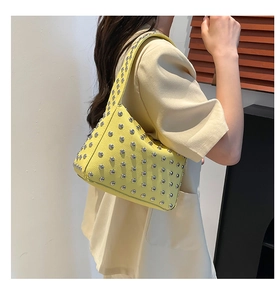 Dettaglio della borsa hobo gialla con borchie argentate su pelle martellata di qualità