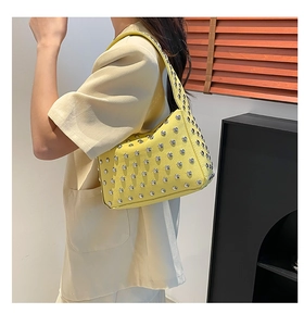 Dettaglio della borsa in pelle martellata giallo vivace con borchie argentate sul manico