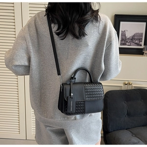 Detail of black woven leather handbag showing fine texture and fashion brand tag