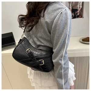 Close-up of black croc-embossed texture and gold metallic buckles on women handbag
