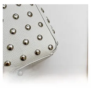 Détail du cuir de lychee blanc avec des rivets en métal argenté et coutures précises