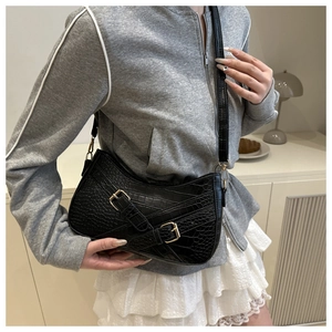 Detailed view of the crocodile texture and golden metal buckles on this black underarm bag