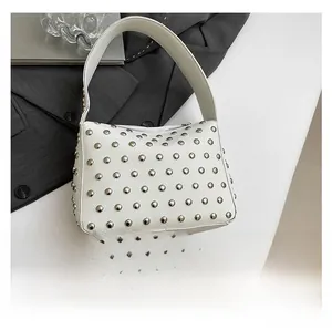 Sac à main blanc clouté avec comparaison de taille par smartphone sur fond élégant