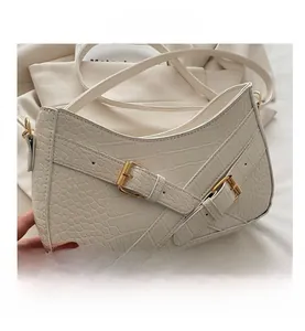 Close-up of crocodile pattern leather and golden buckles on beige shoulder bag