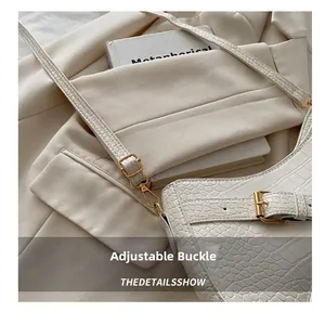 Close-up of crocodile texture shoulder bag with adjustable gold buckle and white strap