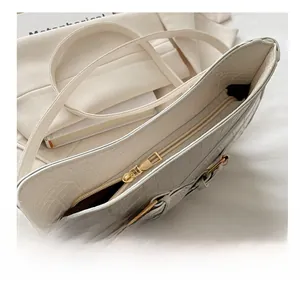 Macro shot of smooth gold zipper and white crocodile pattern leather on crescent bag
