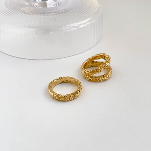 Detailed close-up of three gold rings with unique hammered crater texture on white surface