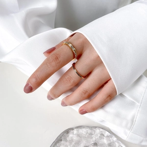 Ensemble de bagues dorées avec zircons rectangulaires et pierres noires sur main