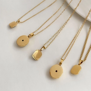 Flat lay of five gold-plated geometric pendant necklaces with emerald and ruby stone accents