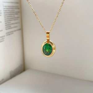 Macro view of oval emerald pendant with ruby accents on a fine gold link chain