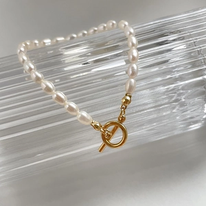 Detailed view of baroque pearl necklace with gold toggle clasp on ribbed glass