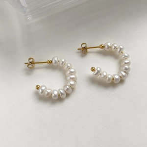 Detail view of C-shaped earrings with baroque pearls and 18K gold plated metal