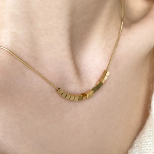 Minimalist gold necklace featuring geometric 3D cubes on a polished snake chain